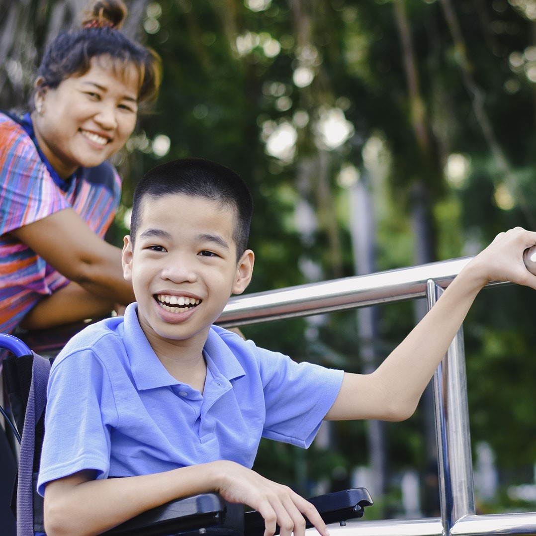 Becoming an NDIS provider, little boy in wheelchair smiling with his carer